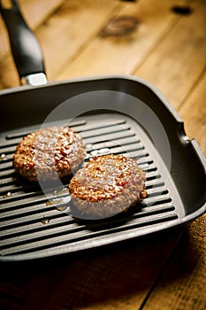 Closeup of juicy burgers fried on black grill pan