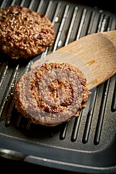 Closeup of juicy burgers fried on black grill pan