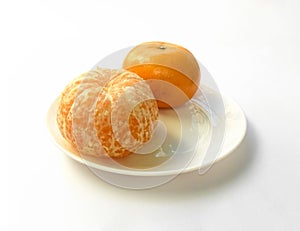 Closeup of juicy ripe orange tangerines (citrus reticula) peeled on a plate with a white background photo