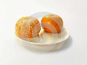 Closeup of juicy ripe orange tangerines (citrus reticula) peeled on a plate with a white background photo