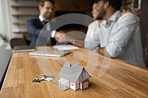 Closeup of keys and toy cottage house on wooden table