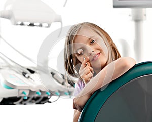 Closeup. Kid girl plays with dental mirror in dentist office