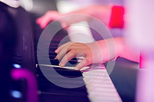 Closeup kid`s hand playing piano on stage with lighting. Favorite classical music