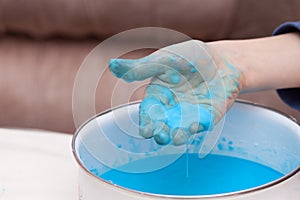 Closeup of kids hand holding blue substance, cornstarch and water mixture, doing a science experiment