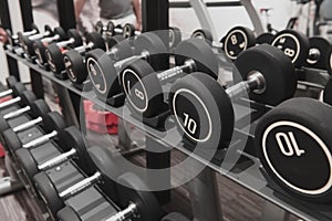 Closeup of kilogram dumbbells placed on a dumbbell rack at the gym. Weight training equipment.