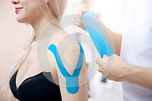 Closeup kinesiology taping to patient shoulder athlete woman