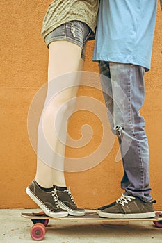 Closeup kissing couple at skateboard and red wall background