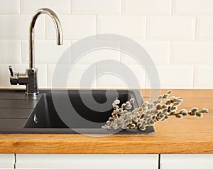 Closeup of kitchen interior. White brick wall, metro tiles. Goat willow in the black sink. Modern Scandinavian design. Home