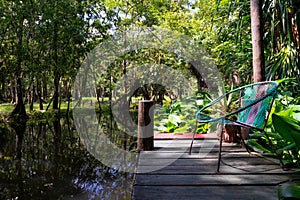 Closeup of a knitted chair on a wooden dock on a lake surrounded by vegetation