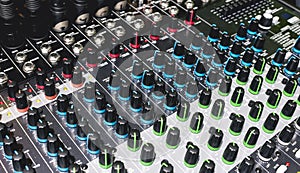 Closeup on the knob controls of a 16 channel digital stereo mixer. Small recording studio setup