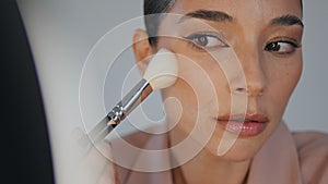 Closeup lady powdering face using brush home. Woman applying foundation makeup