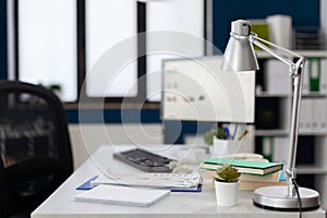 Closeup of lamp on white desk in empty modern business office.