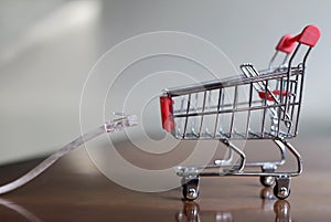 Closeup of a LAN cable and a small shopping cart on the table - concept of online shopping