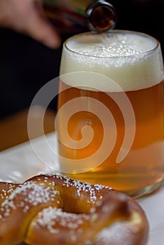 Closeup of a large glass mug of beer and a soft pretzel