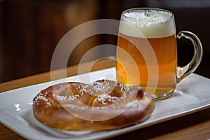 Closeup of a large glass mug of beer and a soft pretzel