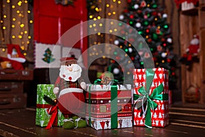 Closeup of a large stack of wrapped Christmas presents of varying sizes and shapes in Xmas interior.