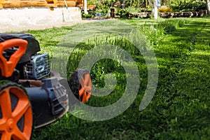 Closeup lawn mower or grass cutter mowing green grass in garden in sunny day. Eco organic environmental sustainability