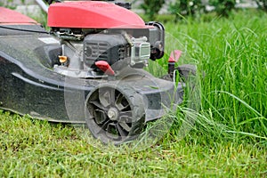 Closeup of lawn mower mowing green grass, city courtyard of an apartment building