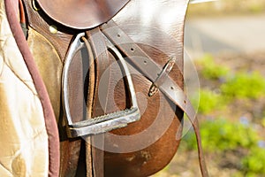 Closeup leather cowboy saddles hanging on the railing