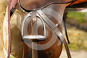 Closeup leather cowboy saddles hanging on the railing