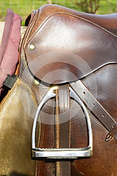 Closeup leather cowboy saddles hanging on the railing