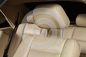Closeup of a leather cream color car seat with a tilted headrest