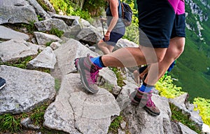 Closeup of a leg with boots or shoes hiking on rocky surface on a mountain during summer. Healthy adventure lifestyle concept