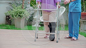 Closeup leg caregiver woman help and support elderly woman while walking with walker for rehabilitation and physical therapy.