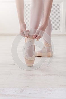 Closeup legs of ballerina puts on pointe ballet shoes