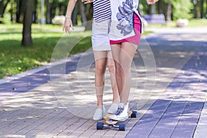 Closeup of Legs of Caucasian and African American Teenager Girl Skating Longboard Outdoors