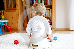 Closeup of legs of cute little 12 months old toddler baby girl child sitting on potty.