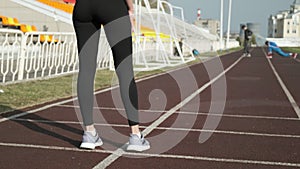 Closeup on legs of fit sportive female in activewear standing at stadium track