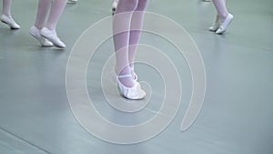 Closeup legs of little ballerinas group in white shoes practicing in ballet school slow motion