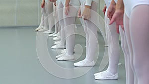 Closeup legs of little ballerinas group in white shoes in row practicing in classical ballet school