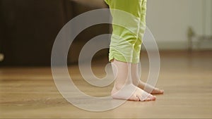 Closeup of the legs of a young child dancing and stomping on a wooden floor in a room