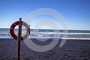 Closeup of a lifebuoy attached to a wooden post at the beach