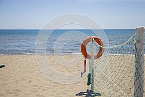 Closeup of lifeguard orange lifebuoy on the beach with sea in th