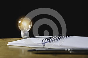 Closeup light bulb on the desk with notebook in office and in financial,accounting,energy,idea concept