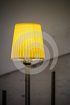 Closeup with lighted yellow lamp. Vertical view with yellow lighted lamp and old walls behind. .