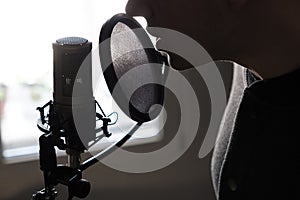 A closeup of lips at the microphone of a young man standing in profile