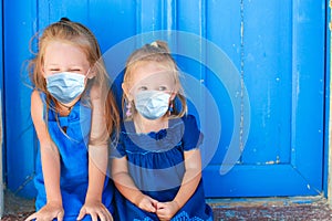 Closeup of Little adorable girls sitting near old blue door in Greek village, Emporio, Santorini