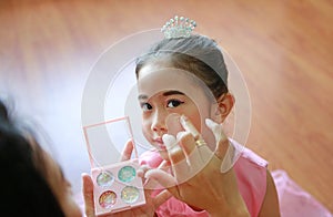 Closeup little Asian ballerina girl with glister makeup by her mother