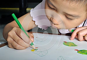 closeup little asian girl hand draw her picture with color pencil