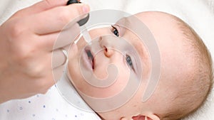 Closeup of little baby boy taking vitamin D from eyedropper. Concept of newborn healthcare and vaccination.