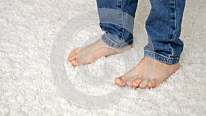 Closeup of little bare child& x27;s feet walking on soft white carpet