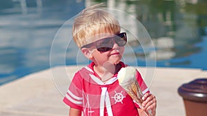 Closeup of little boy with sunglasses eating ice cream at marina