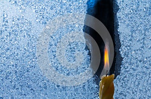 Closeup of little candle flame behind frozen window glass