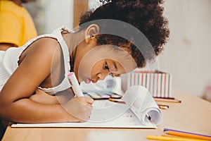 Closeup little child girl black skin writing doing homework at home