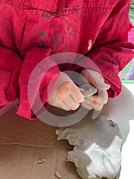 Closeup of little child`s hands working with clay, play dough, on a school or kindergarten activity - learning by doing, education