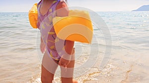 Closeup Little Girl in Armbands Goes out of Sea to Beach